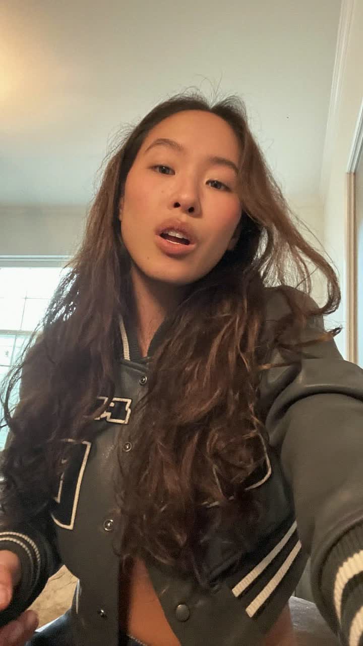 Aoi, 31-year-old Japanese woman, long wavy brown hair, wearing a cropped varsity jacket