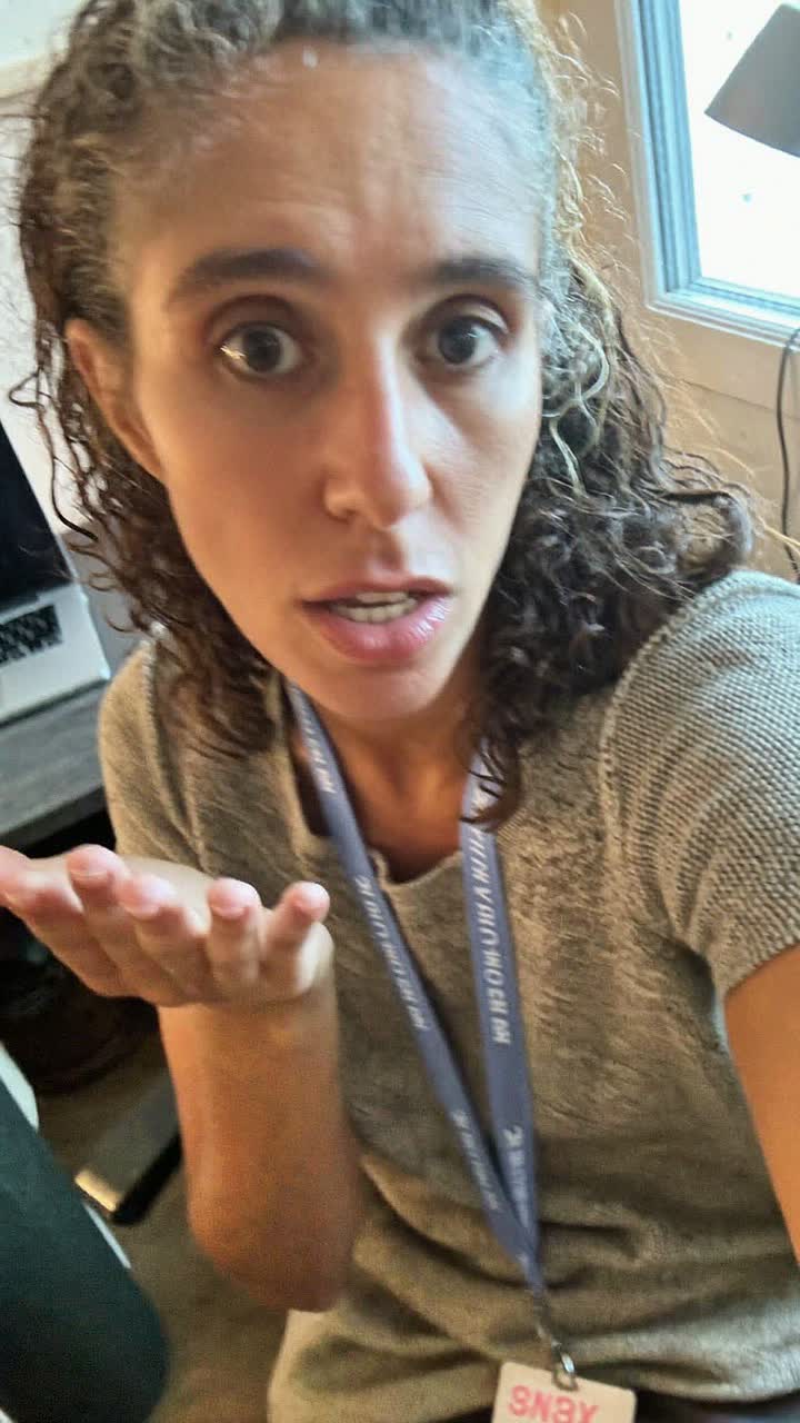 Carmen, 44-year-old Colombian woman, curly hair with a few greys, wearing a teacher's lanyard and a knit top