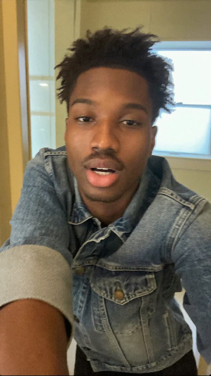 Malik, 26-year-old Black American man, clean-shaven with tousled hair, wearing a denim jacket