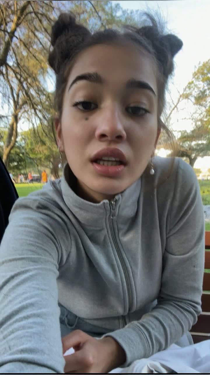 Meera, 21-year-old Indian woman, space buns, wearing a grey zip-up and tiny pearl earrings