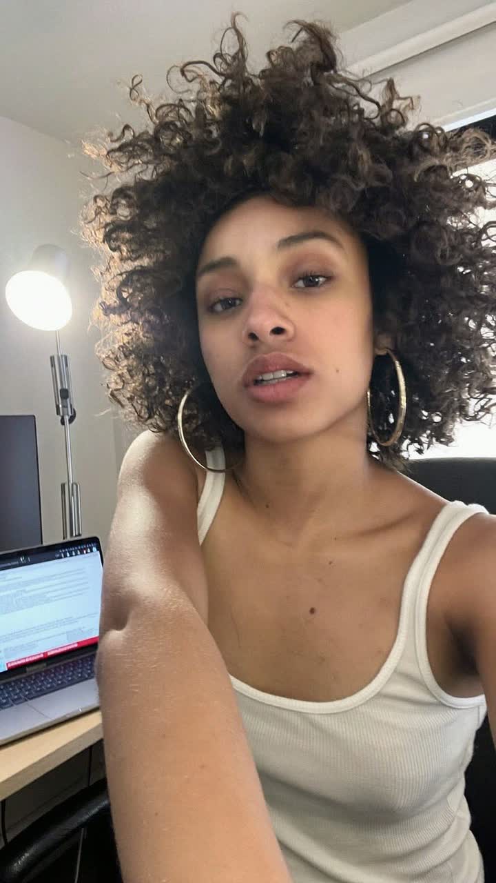 Nicole Rivera, 27-year-old Puerto Rican woman, curly natural hair, wearing a white ribbed tank top and gold hoops