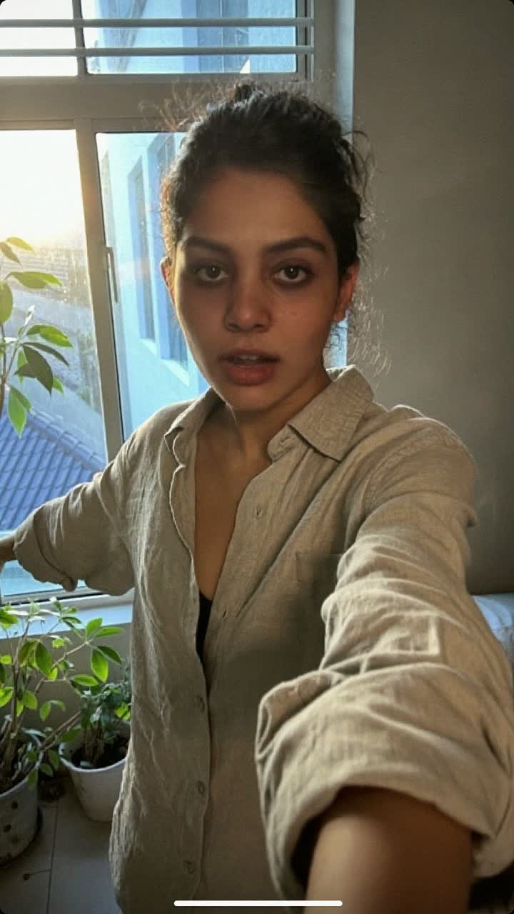 Nisha, 31-year-old Indian woman, messy bun, wearing a linen button-down